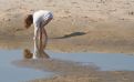 girl bending down at a beach