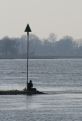 Man sitting at pole by river